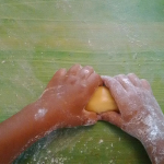 le mani di un bambino sporche di farina mentre impasta